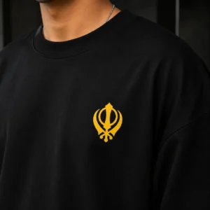 Close up of black oversized t shirt with yellow Khanda left chest logo print